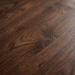 Textural close-up of a premium dark Sheesham wood dining table surface, emphasizing the deep and intricate natural grain patterns.