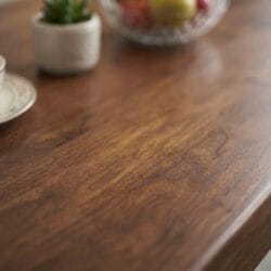 Macro detail shot of a beautifully turned and carved solid wood dining table leg, highlighting premium joinery and natural wood grain.