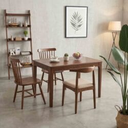 Modern mid-century inspired dining room setup with a solid wood table, curved wooden chairs, and a decorative leaning ladder bookshelf.