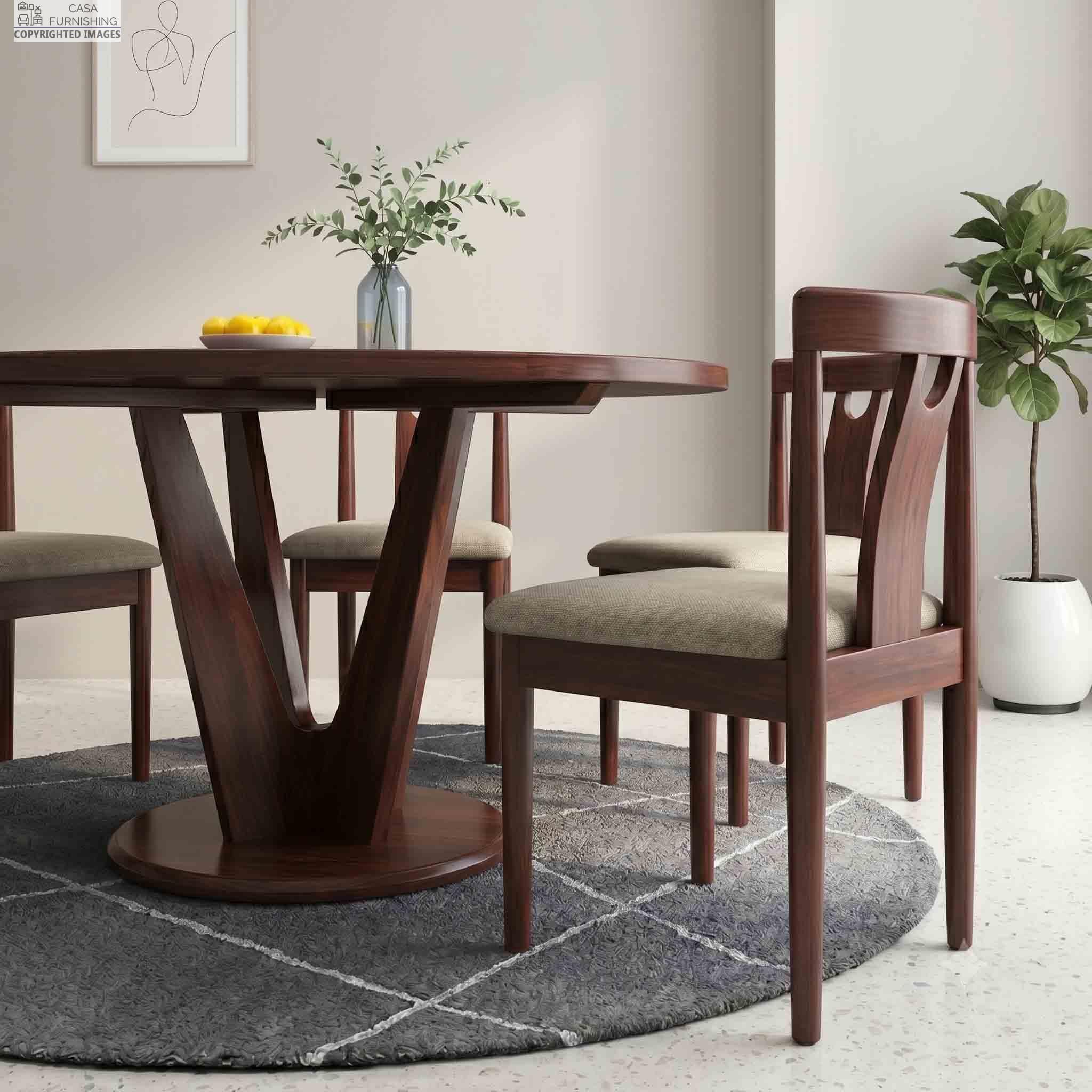 contemporary-sheesham-wood-dining-table-with-v-shaped-pedestal-base Elegant round solid wood dining table set with four upholstered wooden chairs arranged on a circular grey area rug.