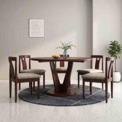 Modern solid wood dining table featuring a unique geometric V-shaped pedestal base and four cream cushioned dining chairs.