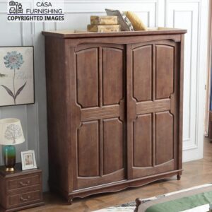 Vintage-inspired solid wood almirah featuring a rich warm brown finish, beautifully styled in a classic bedroom setting next to a matching wooden bedside table.
