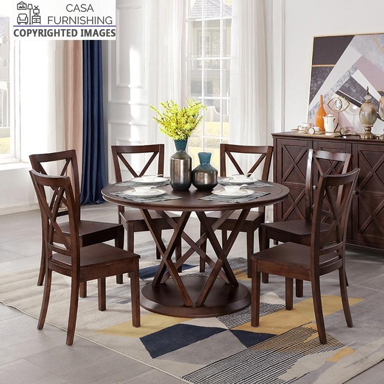 6-seater-round-dining-table-4-1-1-1.jpg Round solid wood 6-seater dining table set with cross-back chairs in a dark walnut finish by Casa Furnishing, featuring a geometric pedestal base.