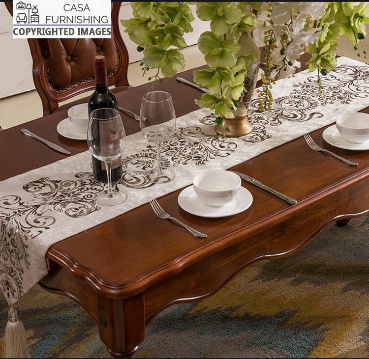 dining-room-sets-4-1-1-1-1.jpg Close-up of a luxury solid wood dining table from Casa Furnishing, featuring hand-carved scalloped edges, a rich mahogany finish, and an elegant table runner for a formal setting.